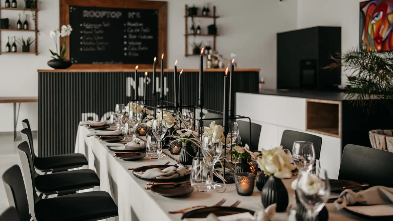 Festlich gedeckte Tafel mit Kerzen vor der Bar im Eventraum